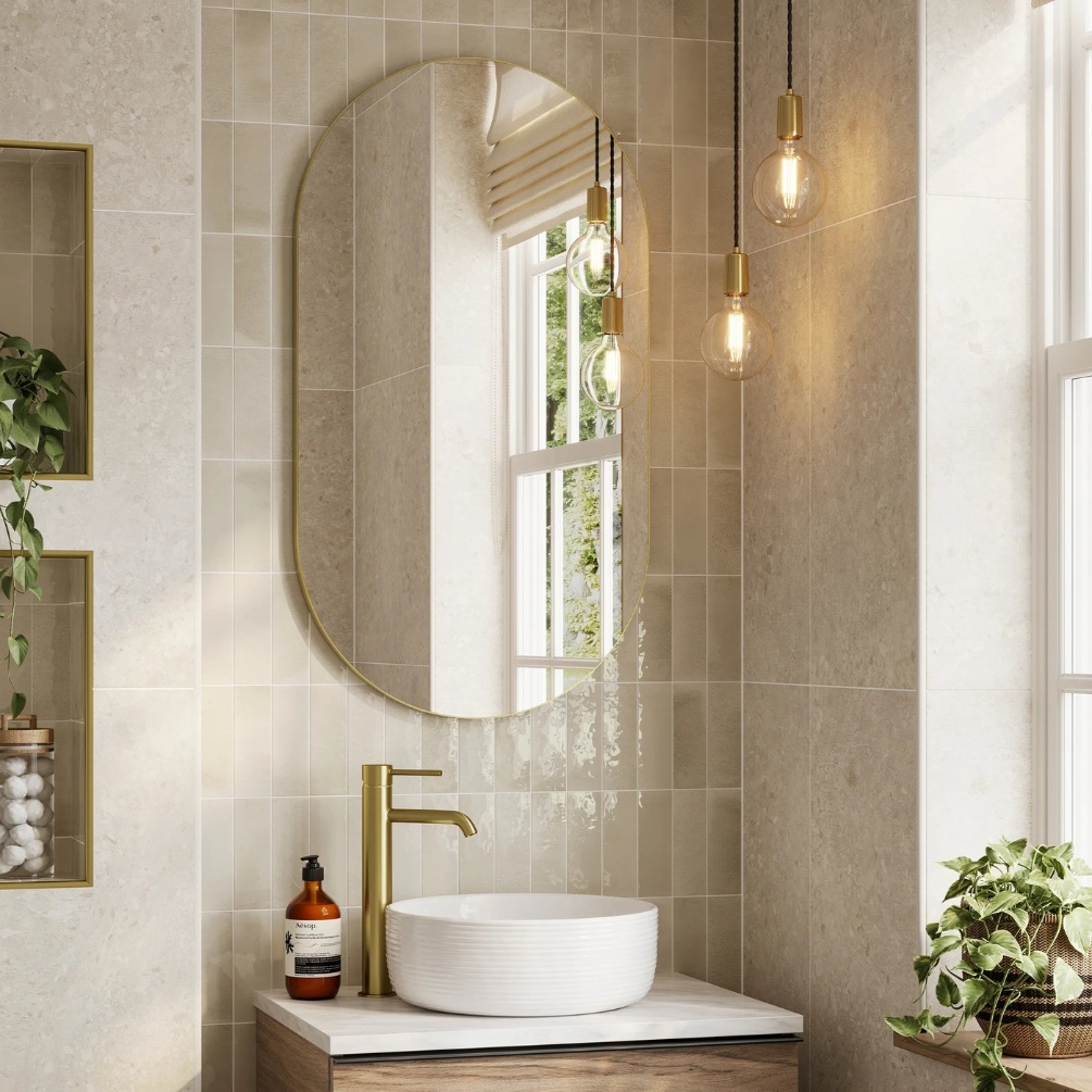 Lifestyle image of the hib. Trim Pill 500mm x 900mm Brushed Brass Bathroom Mirror mounted above a white countertop basin & tall monobloc